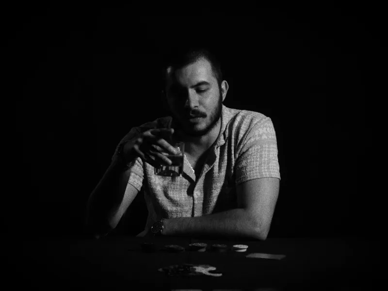 Loş ışıkta, elinde bardakla masada oturan bir adam — Abstre Films çekiminden bir kare